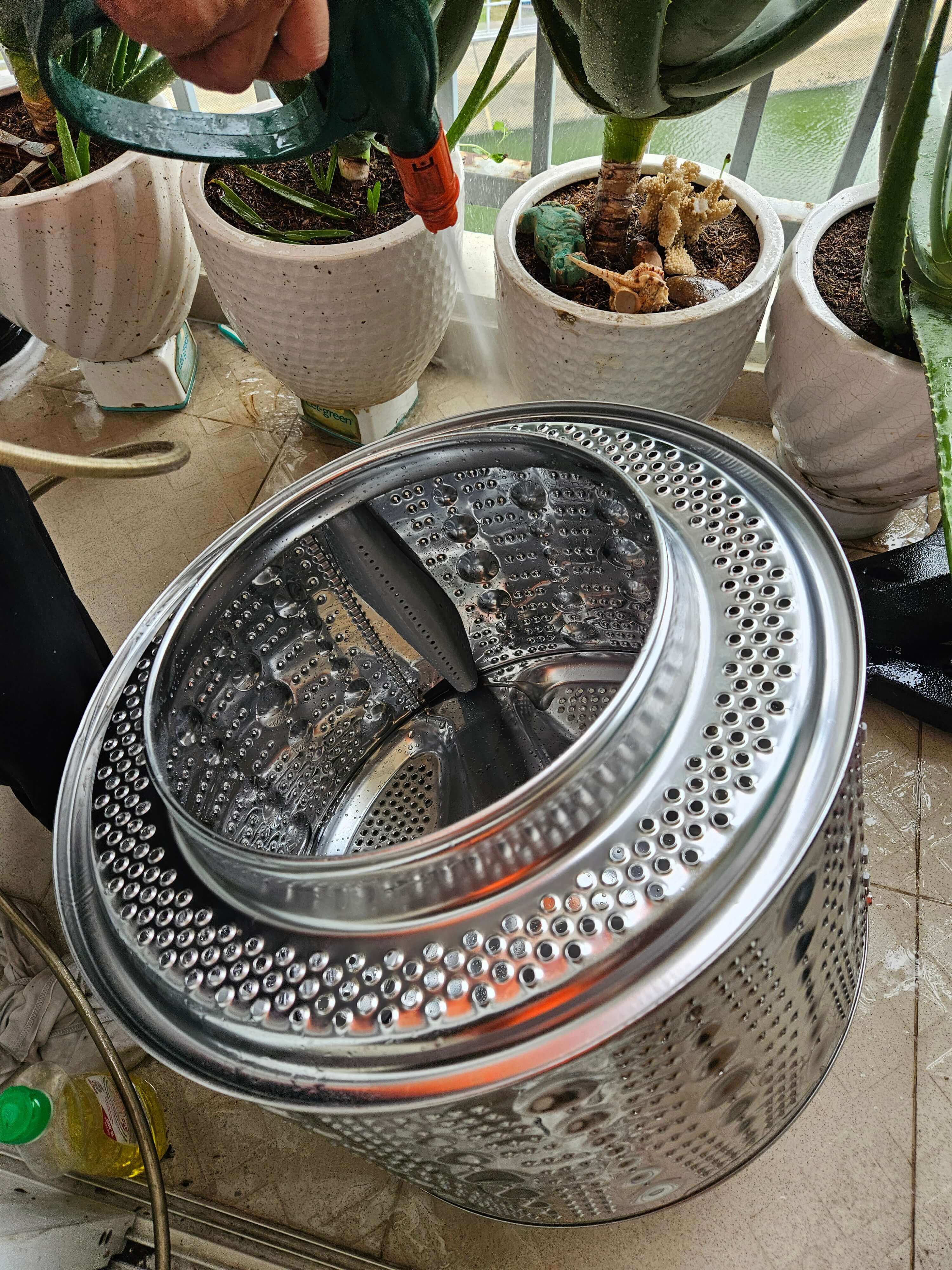 Kỹ thuật viên đang dùng máy xịt áp lực cao vệ sinh lồng giặt